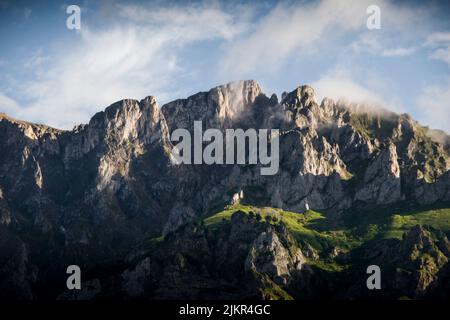 Die Morgenwolken schweben in einem sanften Lichtbild über den felsigen Berggipfeln Stockfoto