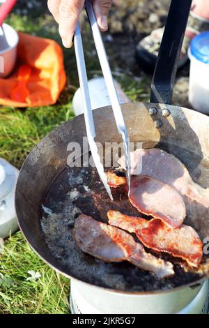Braten Sie Speck auf einem Herd, während Sie in Schottland wild campen Stockfoto