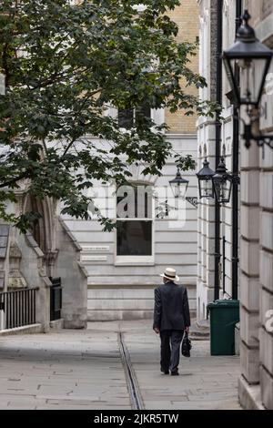 Ein Mann mit einem Trilby-Hut und Aktentasche geht die Temple Middle Lane entlang, einem der wichtigsten Rechtsviertel in London und ein bemerkenswertes Zentrum für Recht. Stockfoto