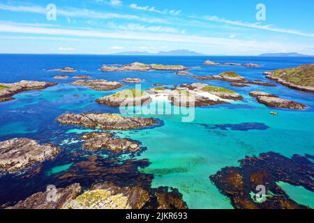 Luftaufnahme der Cairns von Coll, der Inner Hebriden von Schottland mit den Inseln Rum und Eigg im Hintergrund und Sùil Ghorm mit dem Leuchtturm Stockfoto
