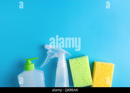 Reinigungsspray, Spülmittel, zwei Schwämme auf blauem Grund. Flach liegend. Stockfoto