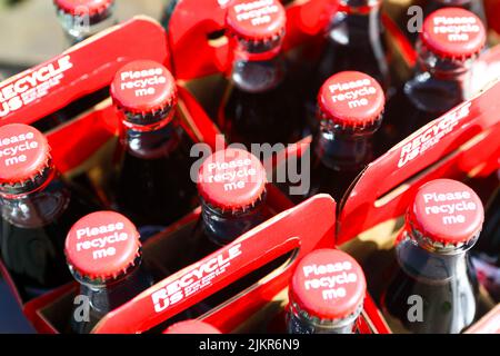 Cola-Flaschen mit Coca-Cola-Drängen zum Recycling, Flaschen, Deckel und Kartonbehälter Stockfoto