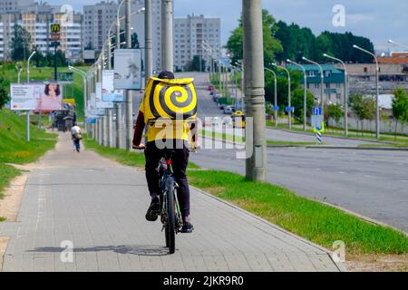 Yandex Eats Food Delivery Courier liefert einem Kunden per Fahrrad eine Bestellung Stockfoto