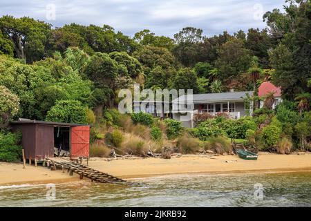 Ulva Island, ein Naturschutzgebiet vor der Küste von Stewart Island, Neuseeland. Das alte Postgebäude der Insel und ein Bootsschuppen Stockfoto