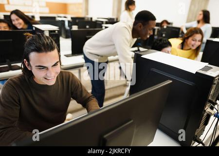 Junge multirassische Studenten, die während der Business-Klasse in der Schule Computer benutzen - Fokus auf linkes Gesicht Stockfoto