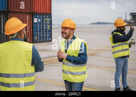 Arbeiter, die Schiffscontainer im Industriehafen im Freien kontrollieren - Fokus auf das indische Männergesicht Stockfoto