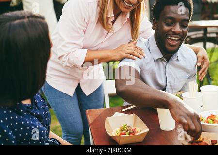 Multirassische Freunde essen im Food Truck Restaurant im Freien - Fokus auf afrikanischen Mann Gesicht Stockfoto