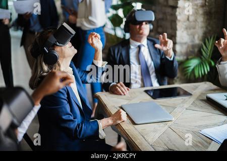 Geschäftsleute, die eine Virtual-Reality-Brille im Büro tragen – konzentrieren Sie sich auf das Headset für ältere Frauen Stockfoto