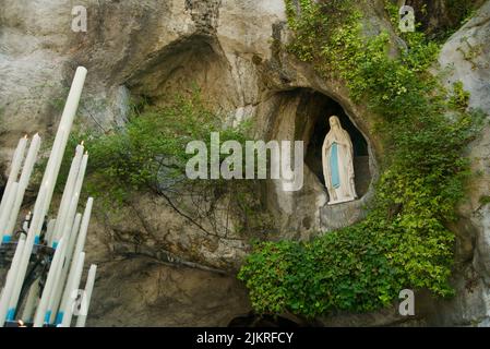 Grotte von Massabielle (Grotte der Erscheinungen) in Sanctuaires Notre-Dame de Lourdes (Heiligtum unserer Lieben Frau von Lourdes) Statue der Jungfrau Maria in Grotte Stockfoto