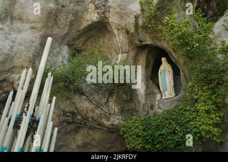 Grotte von Massabielle (Grotte der Erscheinungen) in Sanctuaires Notre-Dame de Lourdes (Heiligtum unserer Lieben Frau von Lourdes) Statue der Jungfrau Maria in Grotte Stockfoto