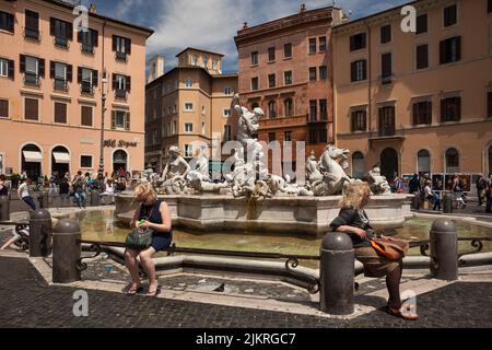 Zwei Frauen sitzen am Neptunbrunnen auf der Piazza Navona, Rom Stockfoto