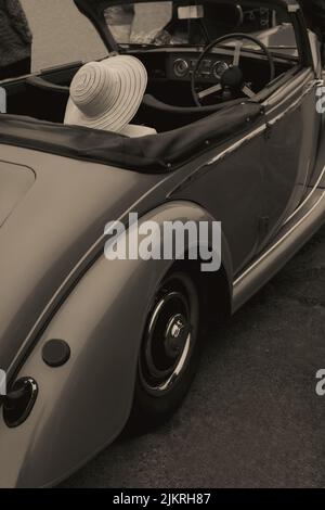Dame mit Sommerhut sitzt im Oldtimer Stockfoto