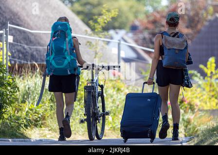 Ahrenshoop, Deutschland. 03. August 2022. Urlauber befinden sich mit Koffer und Rucksack in einem Feriendomizil in der Nähe des Ostseestrandes. Mit Temperaturen von bis zu 35 Grad und wolkenlosem Himmel zeigt sich das Sommerwetter in Norddeutschland von seiner besten Seite. Quelle: Jens Büttner/dpa/Alamy Live News Stockfoto