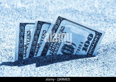 Gelddolare, die halb mit Sand bedeckt sind, liegen in der Nähe des Strandes. Geld wächst aus dem Boden. Dollarscheine teilweise im Sand am Meer verschüttet Strand Konzept Finanzierung Geld Urlaub entspannen Urlaub. Stockfoto