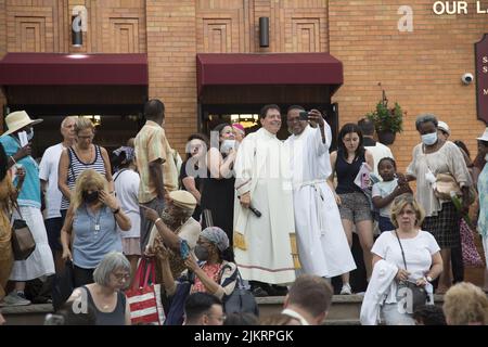 Priester führen eine Prozession vor der Our Lady of Mount Saint Carmel Church beim jährlichen Giglio Feast in Williamsburg, Brooklyn, New York. Selbst Priester nehmen sich Zeit für ein Selfie. Stockfoto