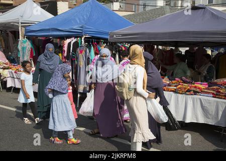 Auf einer Bangladeshi Street Fair auf der Church Avenue im Stadtteil Kensington in Brooklyn, New York, verkaufen Frauen bunte Kleider und Material. Stockfoto