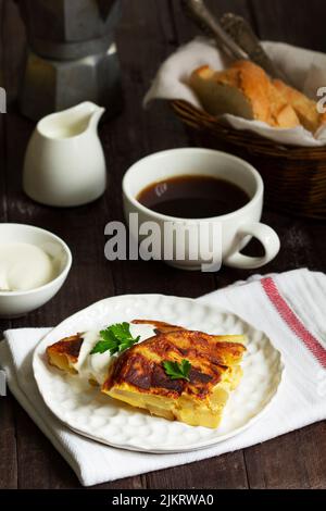 Traditionelles spanisches oder italienisches Omelett mit Kartoffeln, serviert mit Kaffee. Rustikaler Stil. Stockfoto