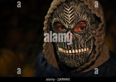 Unschärfe-Nahaufnahme Halloween Menschen Porträt. Person in grimmiger Reaper Maske auf schwarzem Hintergrund stehend. Dunkle Nachtstimmung, Alptraum. Halloween-Horror. Skul Stockfoto