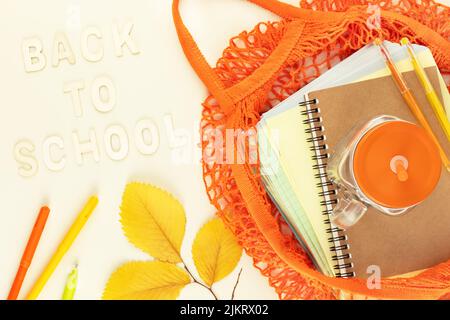 Karte von Zurück zur Schule. Umweltfreundliches Schulverkaufskonzept. Schulbedarf in einem leuchtend gelben Stoffbeutel auf hellem Hintergrund mit Herbstblättern und Stockfoto