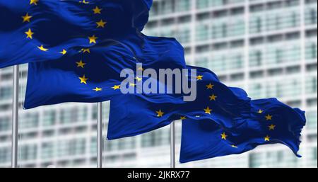 Eine Gruppe von Flaggen der Europäischen Union winkt im Wind vor dem Gebäude des Europäischen Parlaments. Stockfoto
