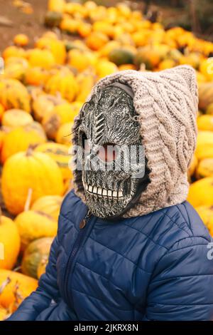 Unschärfe Halloween Menschen Porträt. Person in grimmiger Reaper Maske auf gelbem Kürbis Hintergrund stehend. Halloween-Horror. Schädelgeist. Grimmiger Schnitter. Dämon Stockfoto