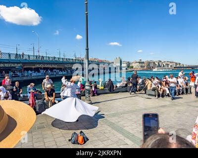 Istanbul, Türkei, 07.14.2022: Wirbelnder Derwisch Sufi religiöser Tanz auf der Fußgängerstraße in Eminonu mit vielen Menschen, die zuschauen. Tourismus Stockfoto