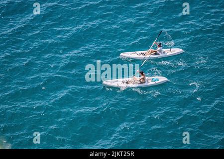 04. Juni 2022, Antalya, Türkei: Zwei Personen auf Kajaks oder sap-Boards schwimmen und reisen entlang der Küstenmeerküste im Resort Stockfoto