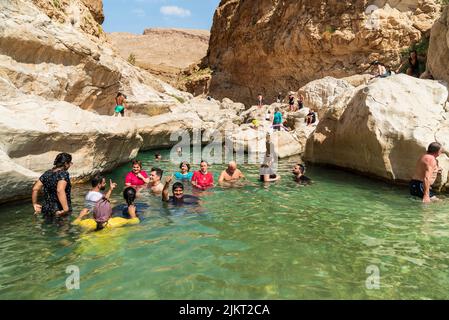 Wadi Bani Khalid, Oman - 12. Februar 2020: Fröhliche Touristen genießen den kristallklaren Wassersee der Oase Wadi Bani Khalid in der Wüste im Sultanat von Stockfoto