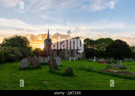 St Laurence and All Saints Church in Eastwood, Southend on Sea, Essex, Großbritannien, bei Sonnenuntergang. Untergehende Sonne hinter Kirchturm. Helles Licht hinter der Kirche Stockfoto