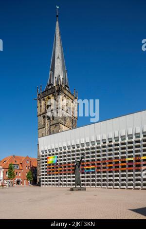 Deutschland, Ahaus, Westmuensterland, Münsterland, Westfalen, Nordrhein-Westfalen, NRW, Katholische Mariä Himmelfahrt-Kirche auf dem Marktplatz stammt der Kirchturm aus der historischen Kirche und das Kirchenschiff wurde von Erwin Schiffer als Betonbau befestigt, vor der Skulptur 'der Mahner' von Hilde Schuerk frisch Stockfoto