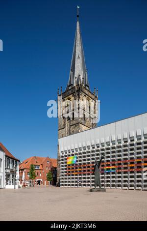 Deutschland, Ahaus, Westmuensterland, Münsterland, Westfalen, Nordrhein-Westfalen, NRW, Katholische Mariä Himmelfahrt-Kirche auf dem Marktplatz stammt der Kirchturm aus der historischen Kirche und das Kirchenschiff wurde von Erwin Schiffer als Betonbau befestigt, vor der Skulptur 'der Mahner' von Hilde Schuerk frisch Stockfoto