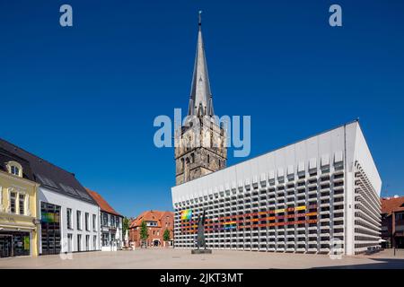 Deutschland, Ahaus, Westmuensterland, Münsterland, Westfalen, Nordrhein-Westfalen, NRW, Katholische Mariä Himmelfahrt-Kirche auf dem Marktplatz stammt der Kirchturm aus der historischen Kirche und das Kirchenschiff wurde von Erwin Schiffer als Betonbau befestigt, vor der Skulptur 'der Mahner' von Hilde Schuerk frisch Stockfoto