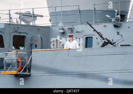 Russland, St. Petersburg, 31. Juli 2022: Der Militärsegler eines Kriegsschiffes steht an Deck eines Schiffes in der Nähe einer Waffe, er ist in einer festlichen weißen Uniform gekleidet Stockfoto