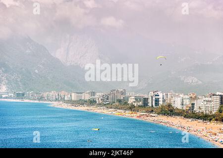 Ein Gleitschirm fliegt über den Strand von Konyaalti in Antalya. Reisen und Urlaub in der Türkei und dem Mittelmeer Stockfoto