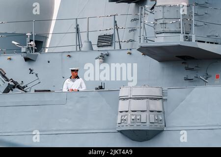 Russland, St. Petersburg, 31. Juli 2022: Der Militärsegler eines Kriegsschiffes steht an Deck eines Schiffes in der Nähe einer Waffe, er ist in einer festlichen weißen Uniform gekleidet Stockfoto