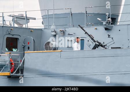 Russland, St. Petersburg, 31. Juli 2022: Der Militärsegler eines Kriegsschiffes steht an Deck eines Schiffes in der Nähe einer Waffe, er ist in einer festlichen weißen Uniform gekleidet Stockfoto