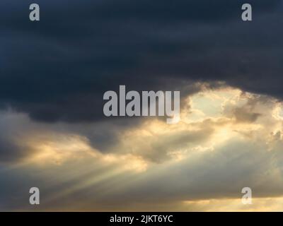 Skyscape mit Sonnenlicht, das durch die bleierne Düsternis schwerer Sturmwolken platzt. Stockfoto