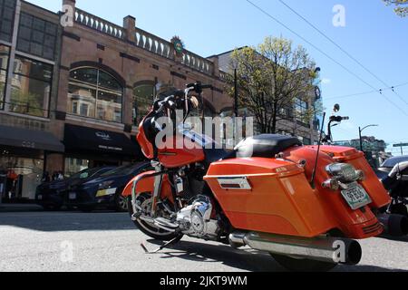 Ein orangefarbenes Harley Davidsson Motorrad in der Straße der Innenstadt von Vancouver in Kanada Stockfoto