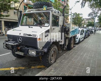 Großer Geländewagen mit Kran in der Stadt geparkt. Der LKW ist weiß Mercedes Benz Unimog von Movistar Telefonica Unternehmen Stockfoto