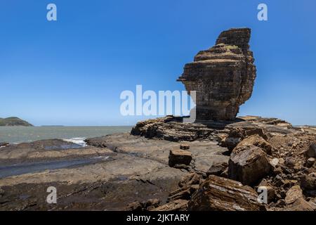 Mann aus Bourail am Strand mit durchbohrten Felsen (Plage de la roche percee) wunderschöner Fels auf dem Meer Stockfoto