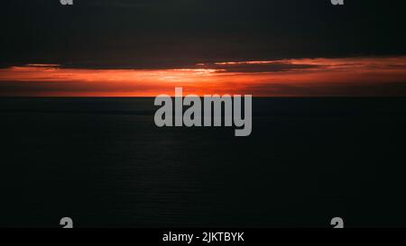Ein schöner Blick auf einen orangen Sonnenuntergang über dem Meer Stockfoto