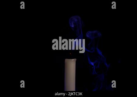 Blauer Rauch von einer erloschenen Kerze im Dunkeln Stockfoto