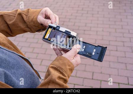 Nahaufnahme eines älteren Mannes, der einen Film in seine alte Kamera legte. Stockfoto