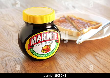 22.. April 2015: Glas Marmite, ungeöffnet auf Holzplatte. Toastscheibe auf einem weißen Teller im Hintergrund. Stockfoto