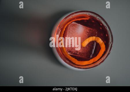 Setzen Sie das G in Negroni, einen Cocktail mit Campari, Gin, Wermut auf Eis mit orangefarbener Tortengarnierung Stockfoto