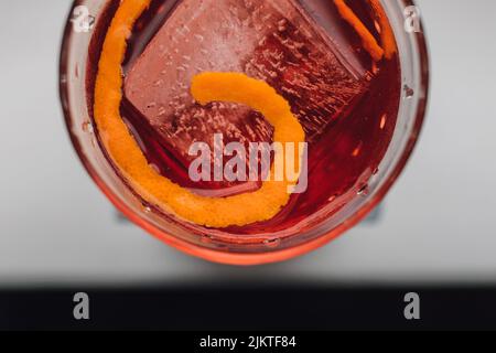 Setzen Sie das G in Negroni, einen Cocktail mit Campari, Gin, Wermut auf Eis mit orangefarbener Tortengarnierung Stockfoto