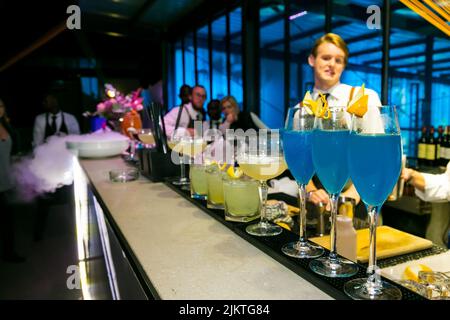 Bunte Getränke an der Bartheke mit Barkeessen im Hintergrund während einer Indoor-Veranstaltung in Johannesburg Stockfoto