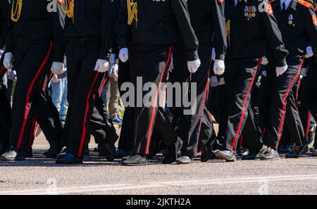 Eine Gruppe junger Menschen, die in blauen Polizeiuniformen gekleidet sind, marschieren die Straße entlang. Der 9. Mai ist jährlicher Feiertag des Siegestages. Stockfoto