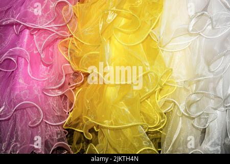 Weiß, gelb, rosa Farben. Abstraktes buntes Muster aus Fragmenten luftiger Tüllstoffe. Nahaufnahme. Selektiver Fokus. Stockfoto
