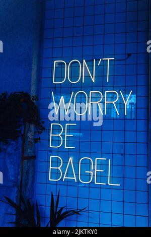 Eine vertikale Aufnahme einer „ALSO KEINE SORGE, SEI BAGEL“-Botschaft aus Laserlichtern an einer Wand Stockfoto